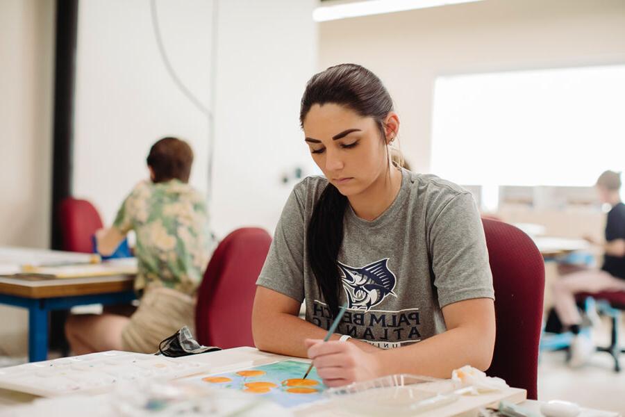 an art education student painting at a table